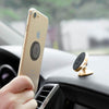Magnetic cell phone holder mounted on car dashboard holding gold smartphone for hands-free use