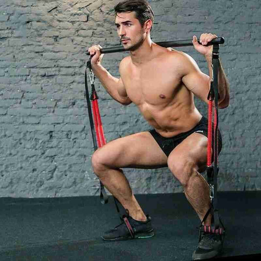 Man using Pilates Bar Kit with resistance bands for squat exercise at home gym