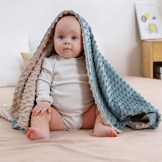 Baby wrapped in super soft double-layer baby blanket with dotted backing on bed
