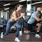 Two people exercising in gym using ankle strap resistance bands for leg and hip strength training
