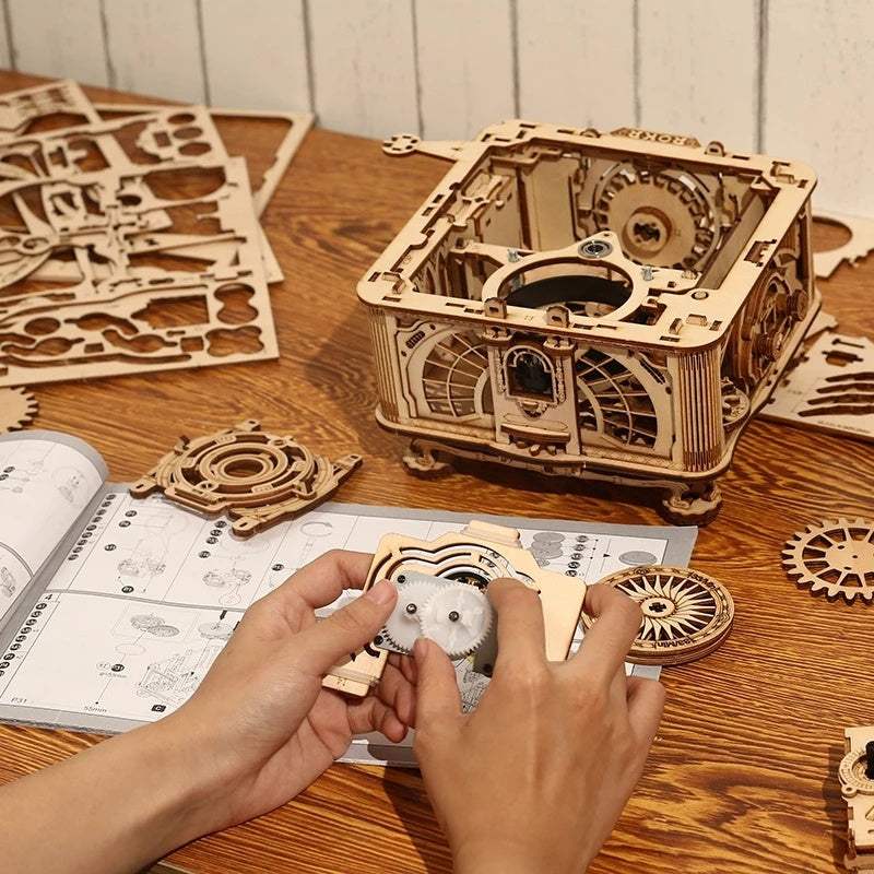 Robotime ROKR DIY wooden mechanical puzzle model being assembled by hands on a table with instruction manual and wooden parts around