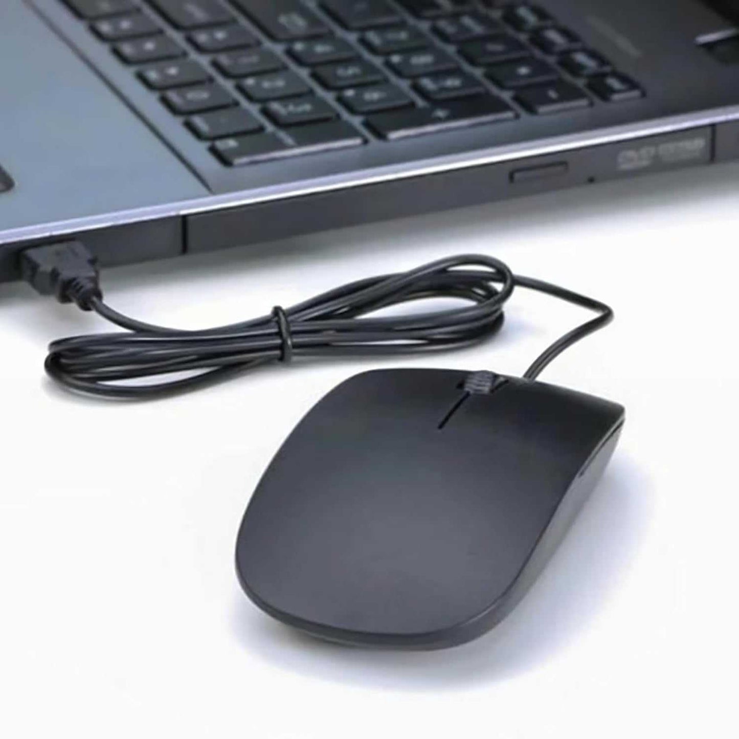Black ultra-slim optical mouse with scroll wheel and USB cable connected to laptop