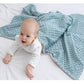 Baby wrapped in super soft double-layer blue baby blanket with dotted texture on white bed